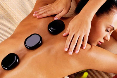 Mulher recebendo uma massagem relaxante com pedras quentes alinhadas em suas costas para alívio de tensão.