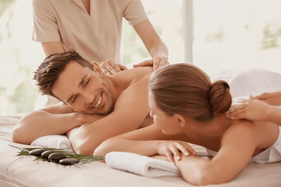 Casal sorrindo enquanto recebe uma massagem relaxante lado a lado em um spa de luxo.
