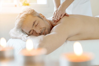 Massoterapeuta aplicando massagem de ponto-gatilho no ombro de um homem para liberação miofascial e alívio de dor.