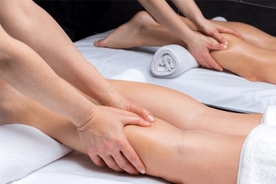 Close-up de duas pessoas recebendo massagem nas pernas ao mesmo tempo para recuperação muscular e alívio do cansaço.