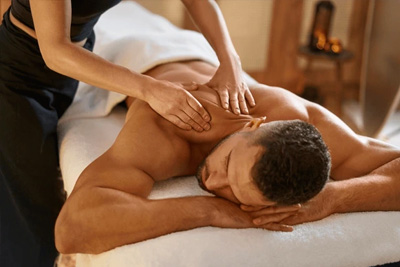 Homem atlético recebendo uma massagem profunda nas costas para recuperação muscular em uma clínica de massoterapia.
