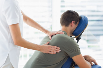 Homem recebendo uma sessão de Quick Massage nas costas e ombros por uma terapeuta em um ambiente profissional.