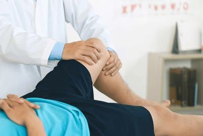 Fisioterapeuta examinando o joelho de um paciente para avaliar uma lesão e verificar a amplitude de movimento.