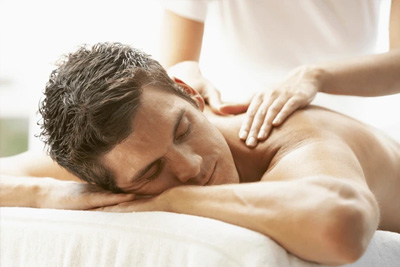 Homem recebendo uma massagem desportiva nos ombros para liberação de tensão muscular em um ambiente relaxante.