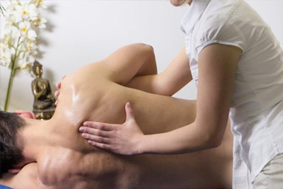 Terapeuta realizando uma massagem com alongamento no ombro de um cliente deitado de lado para aumentar a flexibilidade.