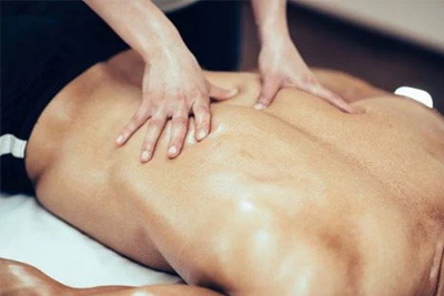 Close-up das costas de um homem recebendo uma massagem relaxante com óleo para alívio de dores e estresse.